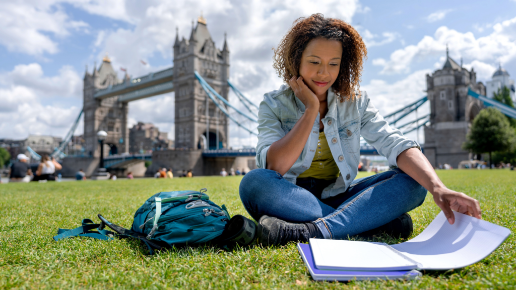 A black girl studying in front of the Tower Bridge in London.