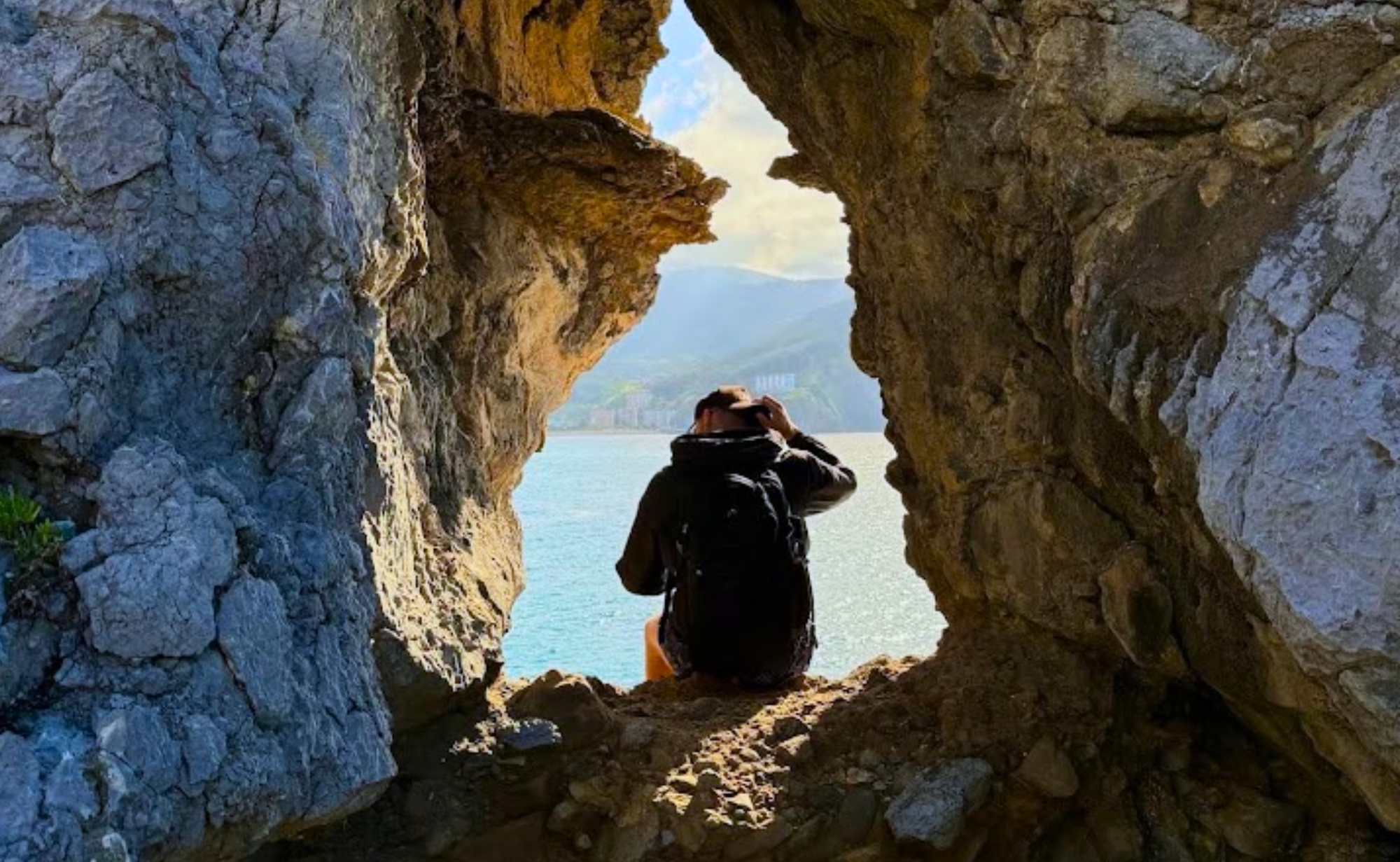 Student surrounded by rock overlooking a body of water